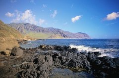 rocky shore line with mountains in background in honolulu hawaii